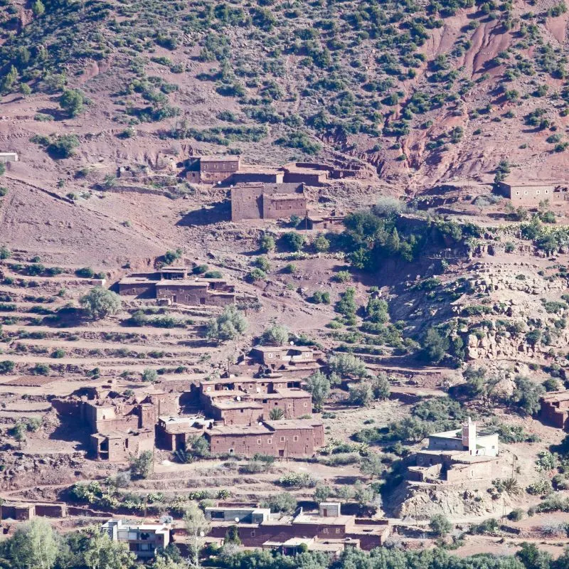 A Berber village of red clay houses among terraced fields on a hillside above the Ouirgane valley