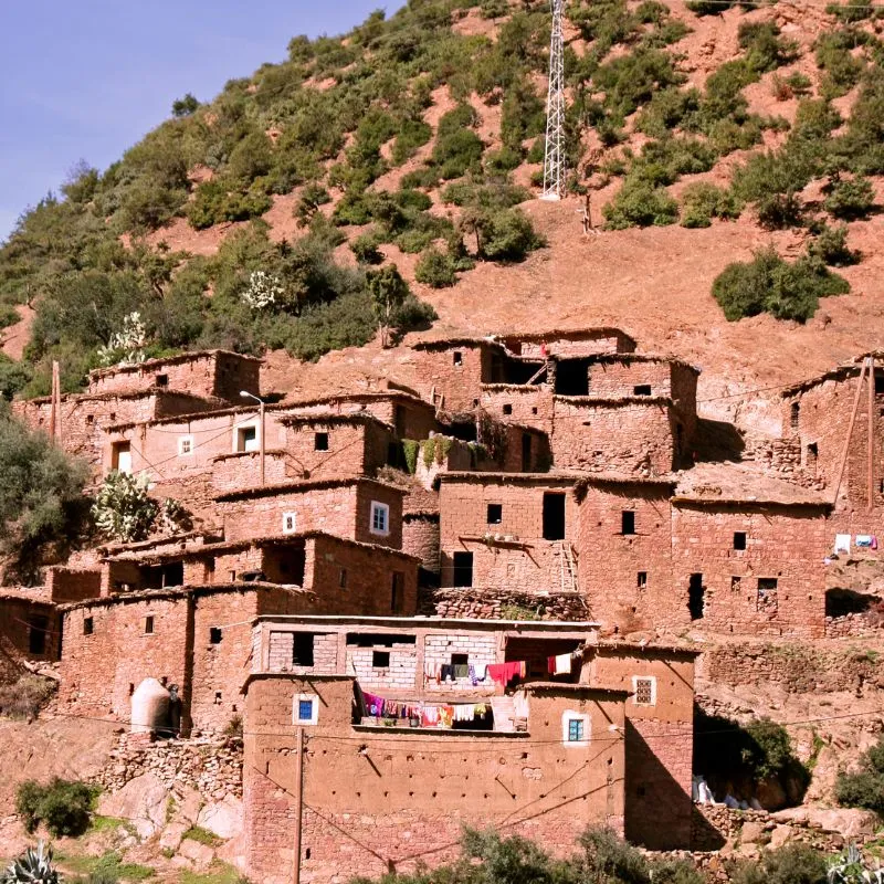Red clay Berber houses stacked up a hillside with washing hung out along a terrace