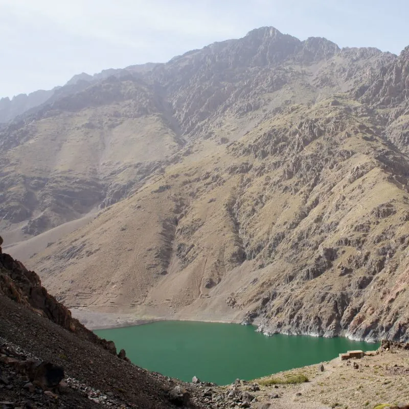 The green water of Ifni Lake below steep scree slopes in the High Atlas